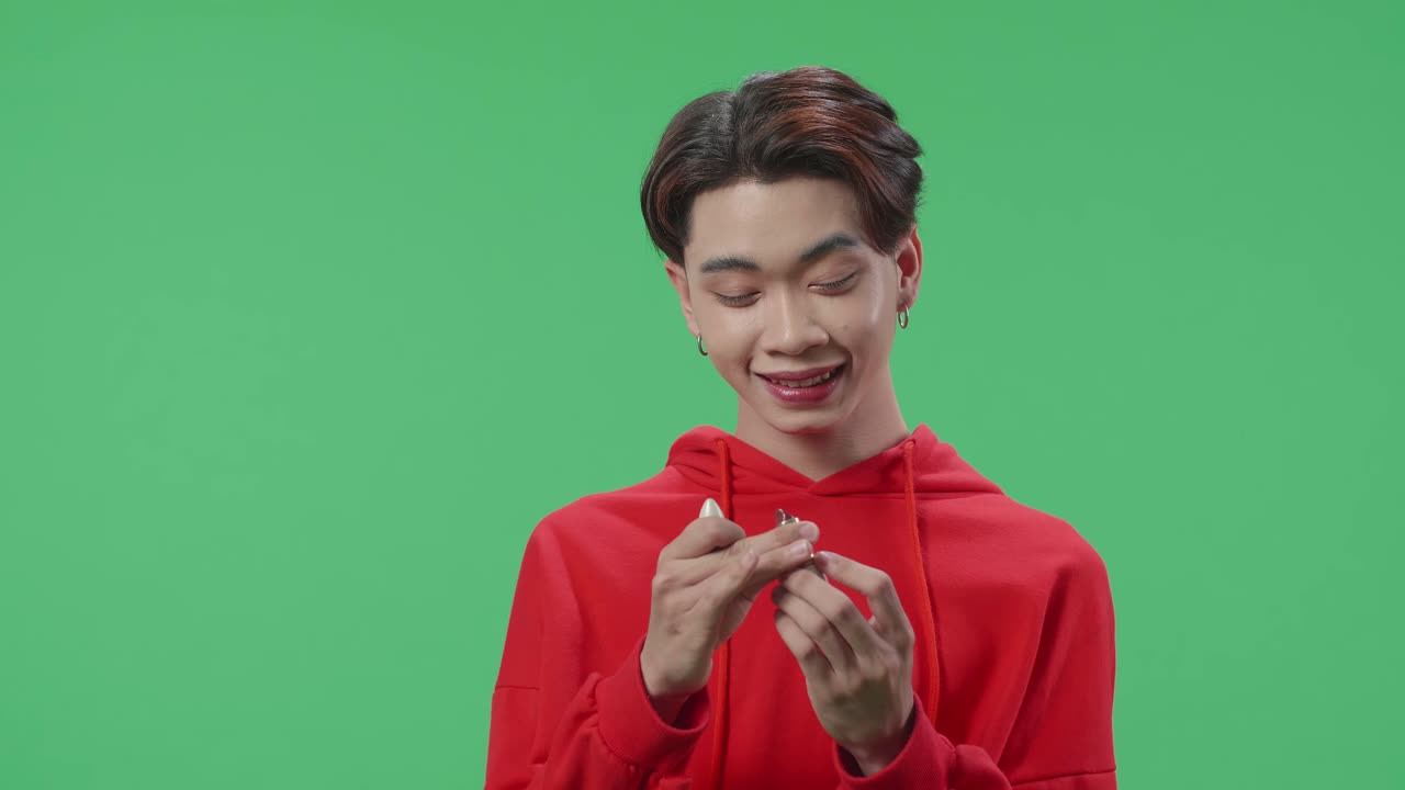 Asian Transgender Guy Applying Lipstick In The Green Screen Studio