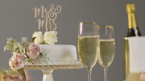 wedding cake with glasses of champagne against grey studio background at wedding reception 1