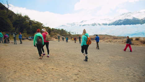 wide view of group of tourists walking toward perito moreno glacier, patagonia, argentina