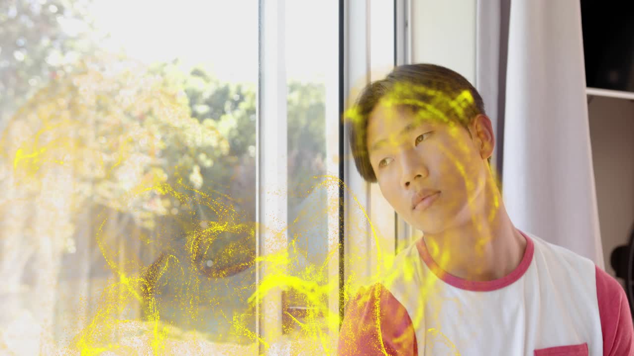 Teenage boy turning at window as yellow particles appearing, curling over face for tech demo