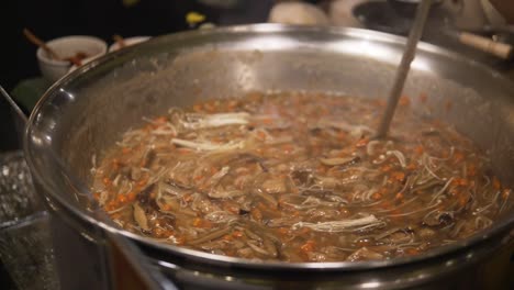 Una-Mujer-En-Bangkok-Está-Cocinando-Comida-En-Una-Olla-Tradicional-Tailandesa,-Mientras-La-Revuelve