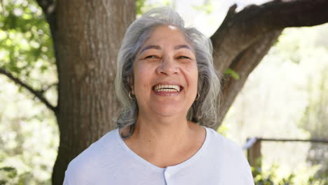 Retrato-De-Una-Feliz-Mujer-Birracial-Mayor-Con-Pelo-Gris-En-La-Naturaleza-Soleada,-Espacio-Para-Copiar,-Cámara-Lenta