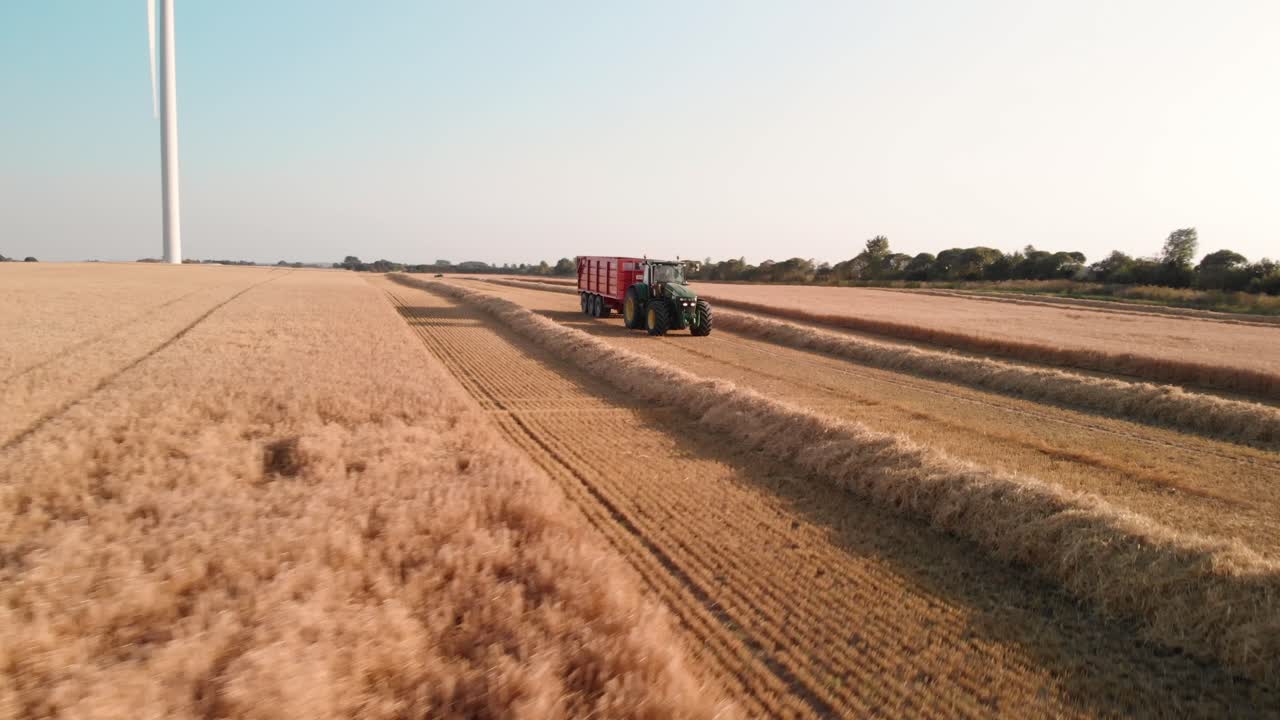 Tractor driving on a field assisting in the harvest