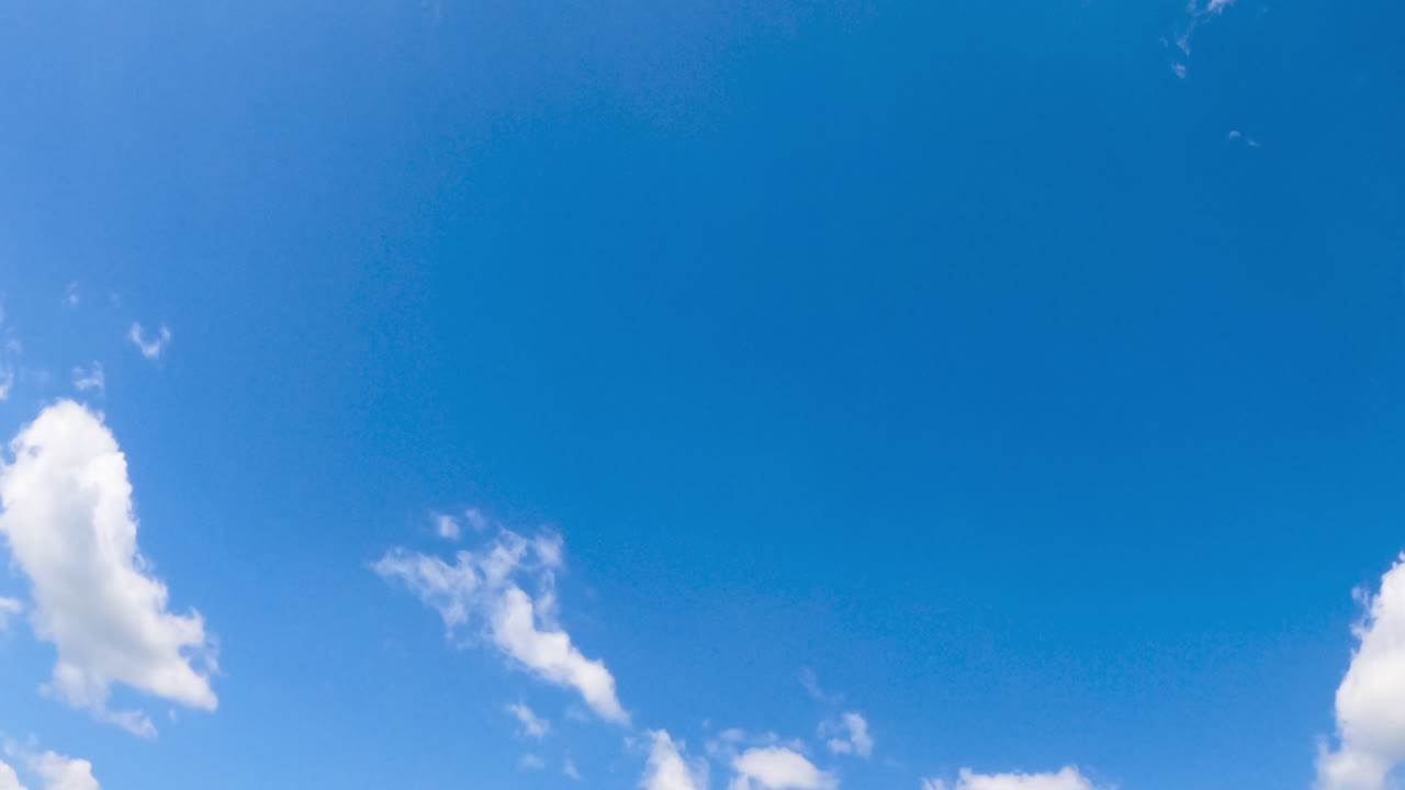 Soft white clouds floating in the blue sky. Summer sky with cotton clouds from low angle view. Timelapse.