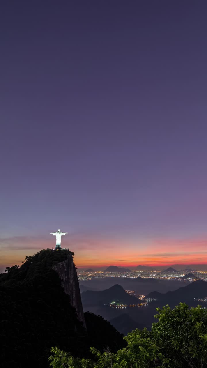 Aerial video shot at sunset captures the iconic statue atop a mountain, overlooking a cityscape