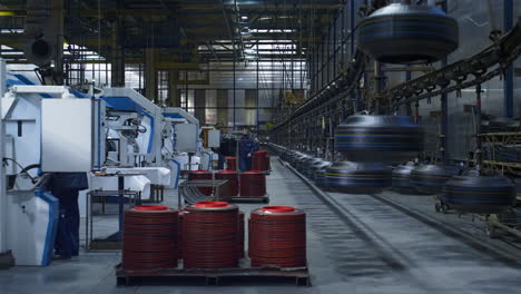 employee in tire factory walking at background with new black rubber product