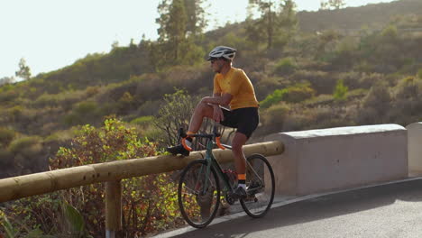 after reaching his destination, a man on a bicycle pauses to appreciate the breathtaking mountain view