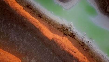 los ojos de los pájaros aterrizan en un desierto dorado con un lago de agua de lluvia verde moviéndose hacia abajo al atardecer