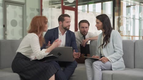 work team composed of two females and two males around a laptop put issues in common 2