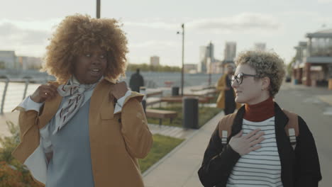 multiethnic female friends walking outdoors and chatting