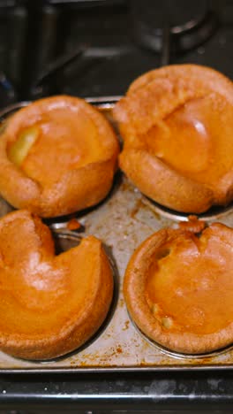 vertical video overhead view of perfect golden british yorkshire puddings after cooking in tray resting on kitchen stove. tradtional english cuisine served with roast dinners.