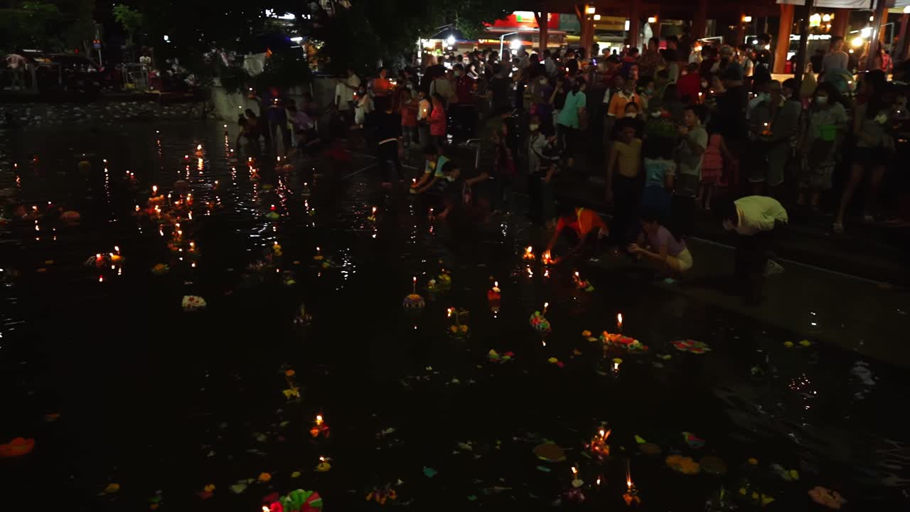 People pray and put floating candles on City Canals during Loi Krathong celebrations in Korat, Thailand. Crowd Celebrates a traditional Thai holiday. River full of beautiful Krathongs. 4k