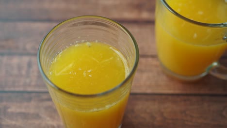 two glasses of orange juice on a wooden table