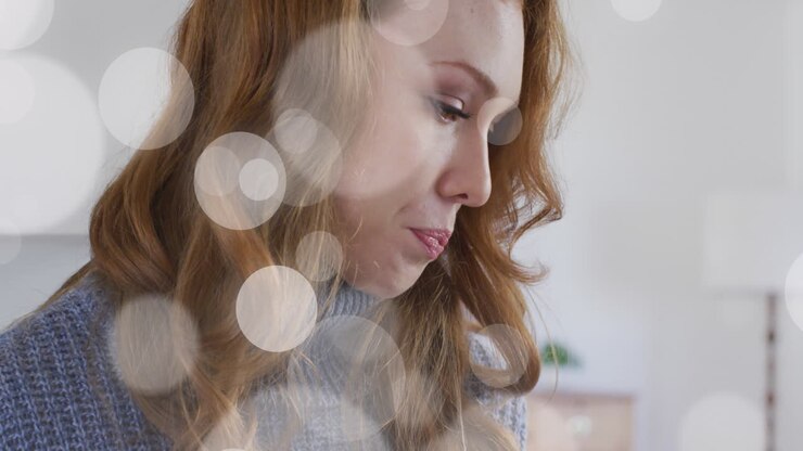 Animation of light spots over caucasian woman drinking coffee in kitchen