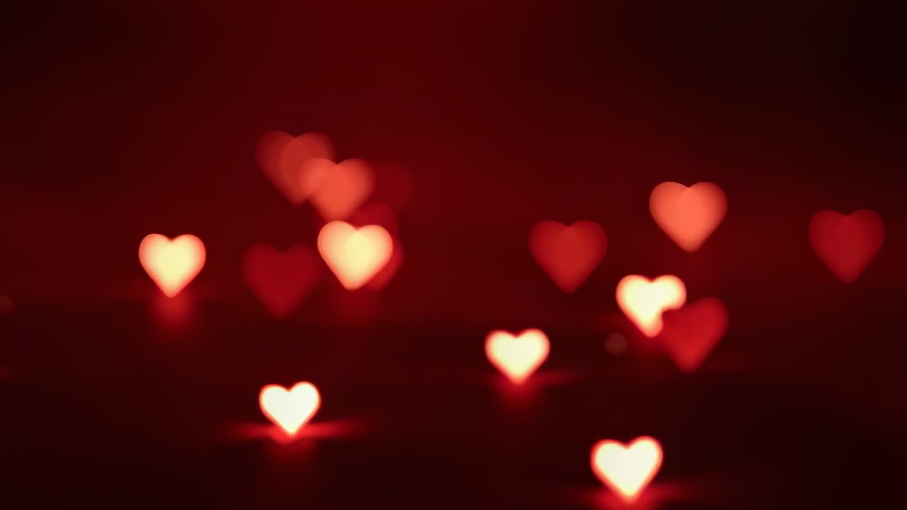 Luci bokeh a forma di cuore fluttuanti che si spostano e pulsano come la luce che si sposta in uno studio buio con apertura a forma di cuore