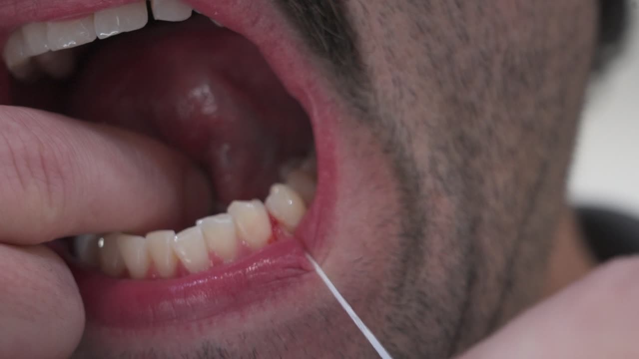 A man with sensitive gums flosses close up