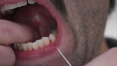 a man with sensitive gums flosses close up