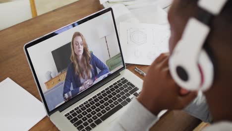 Estudiante-Universitario-Afroamericano-Sosteniendo-Notas-Mientras-Realiza-Una-Videollamada-En-Una-Computadora-Portátil-En-Casa