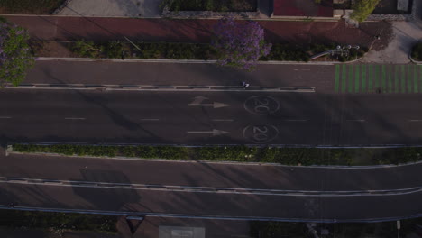 Aerial-right-to-left-panning-overhead-view-white-car-drive-in-street-pass-on-main-road