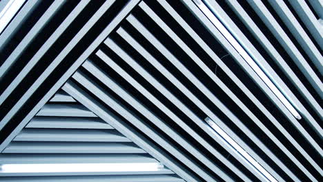non-standard decoration of the ceiling with white planks. long lamps with white light among the ledges. low angle view.