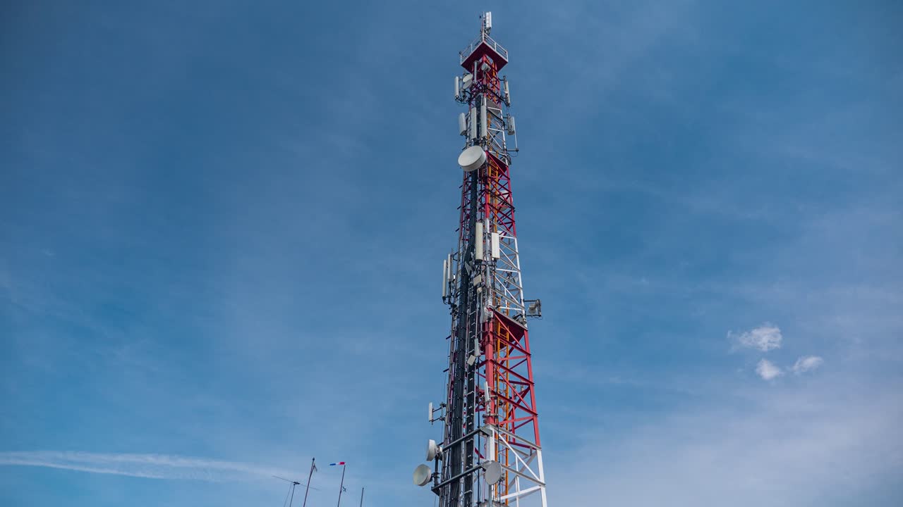 lapso de tiempo de una torre de telecomunicaciones con antenas 5g cubiertas por nubes de niebla que se mueven rápidamente contra el cielo azul