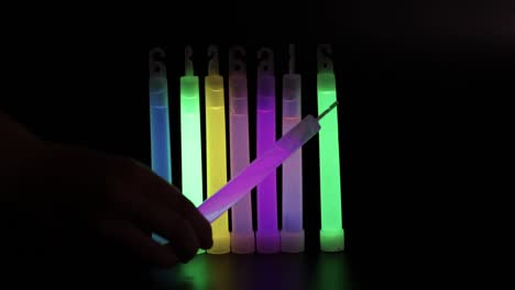 hand arranging glowing sticks in various colors