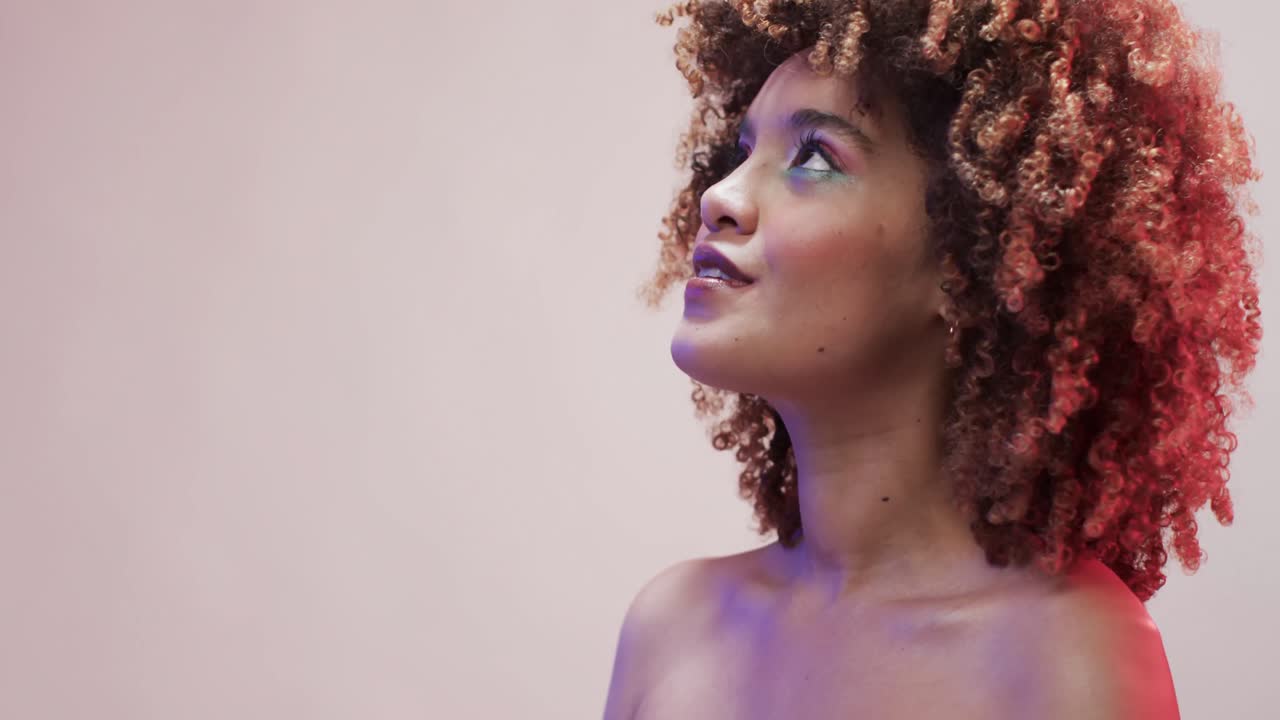 mujer biracial con cabello oscuro en luz azul y rosa con espacio de copia, cámara lenta