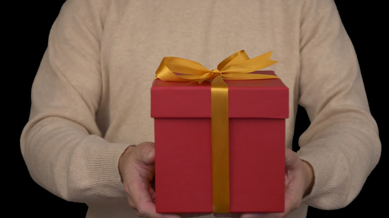 hombre caucásico en suéter beige está sosteniendo una caja de regalos en las manos. vista frontal de hombre en suéter beige casual. hombre da un regalo. canal alfa clave de croma fondo transparente. cerrado.