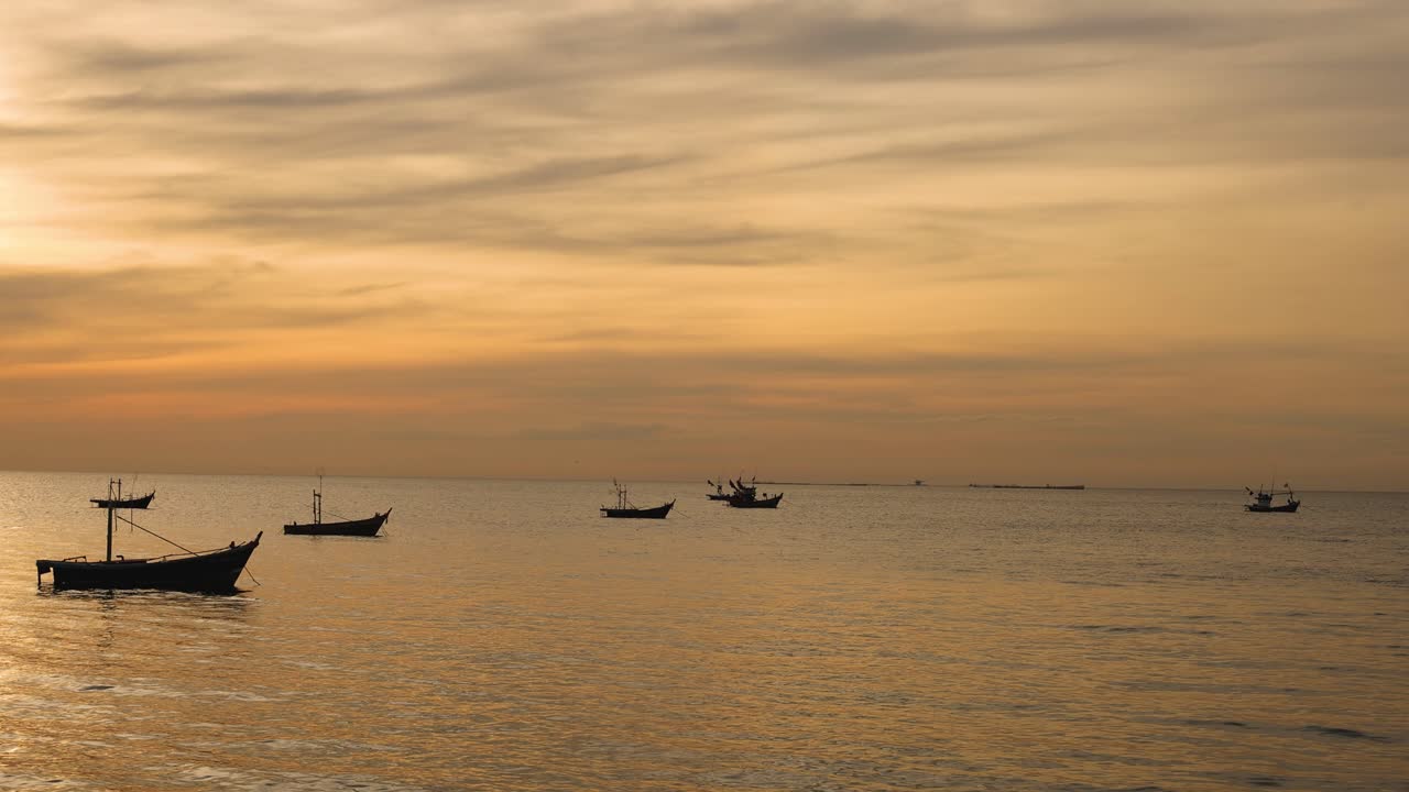 보트들은 황금빛 해가 지는 아래 평화롭게 떠다니고 있습니다.