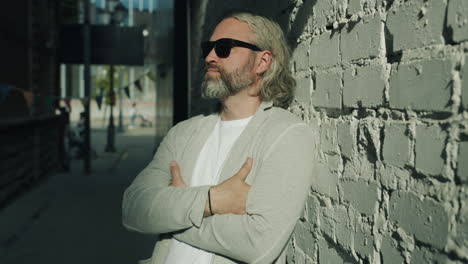 stylish man posing by a brick wall