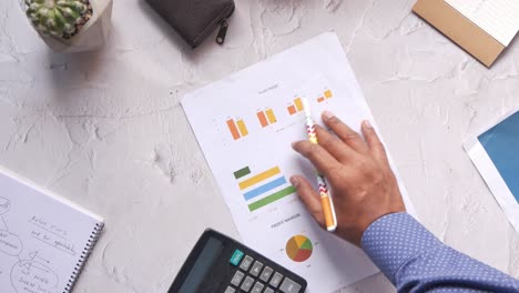 Man-hand-with-pen-analyzing-bar-chart-on-paper