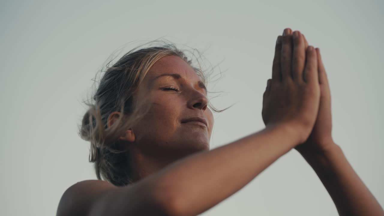 mujer practicando yoga saludo al sol afuera con viento que sopla el cabello, namast?