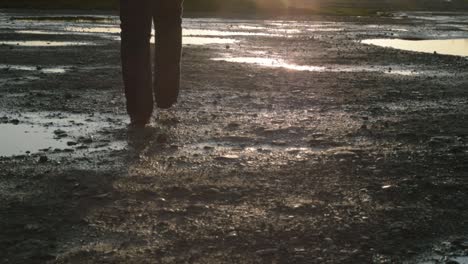 person walking across lonely deserted wasteland at sunset