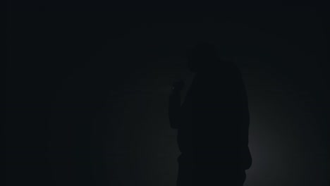 silhouette of man smoking in dark room