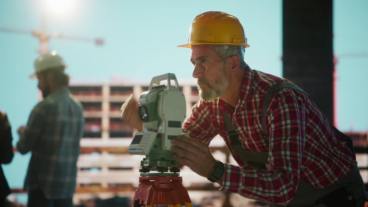 Professional surveyor using a total station on a construction site with a team