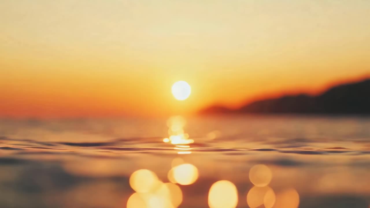 A serene sunset over the ocean with a low-angle view, capturing the horizon in a warm, cinematic