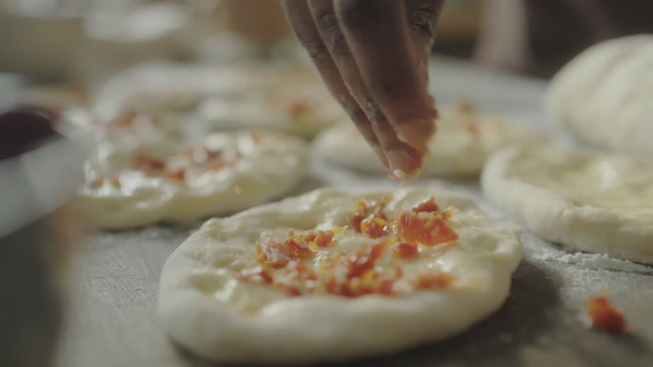 Mano che sparge condimenti su mini pizze