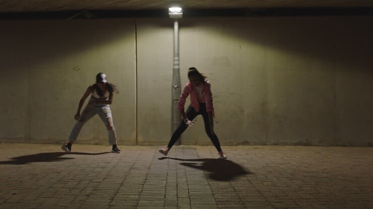 donna ballerina giovane ballerina hip hop ragazze sotto la luce della strada che praticano movimenti di danza contemporanea freestyle che si esercitano in città di notte