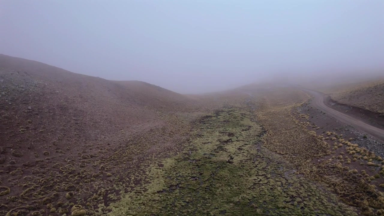 4K drone aerial view of the road to San Antonio de los Cobres, Salta, Argentina. Dramatic fog and low clouds covering the mountains create a mysterious Andean landscape.