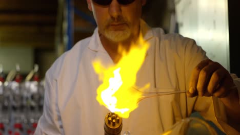 front view of mature male worker blowing glass in glass factory 4k