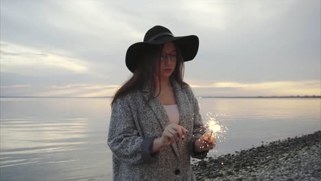 mujer con chispas al atardecer en la playa