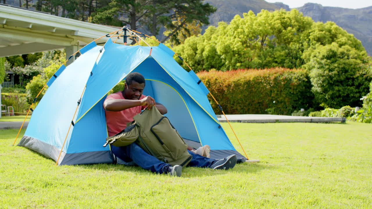 African American, Father and daughter enjoying camping in backyard, unpacking gear from tent