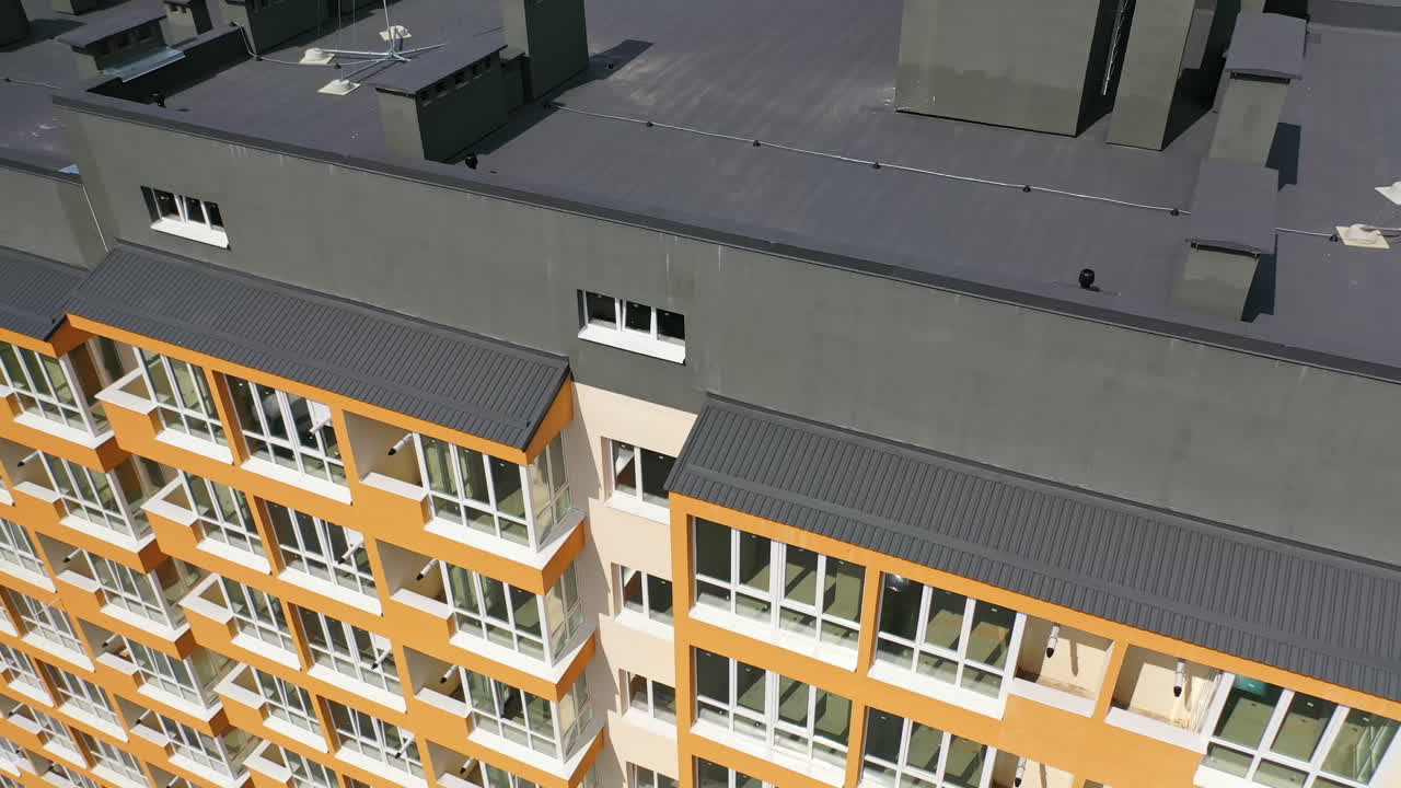 Beautiful design of multistory building. New apartment with balconies against blue sky. Exterior of residential building. Camera rising up. Slow motion