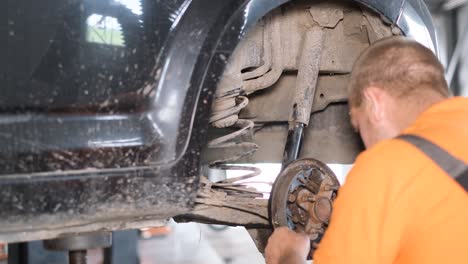 mechanic working on car suspension and wheel in a garage