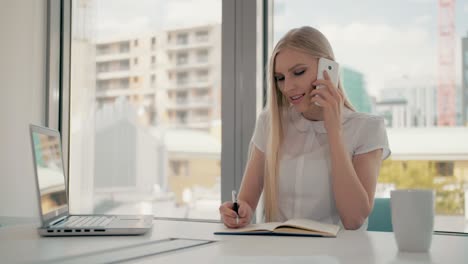 серьезная женщина, работающая в светлой офисной комнате. элегантная современная бизнес-женщина с ноутбуком и бумагами за длинным столом в конференц-зале с телефонным звонком