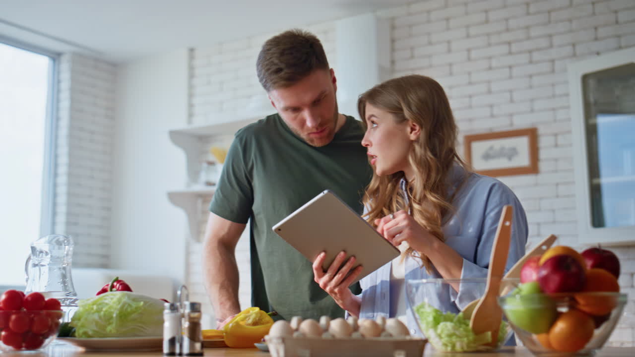 Closeup couple choosing recipe for dinner at home. Happy spouses cooking food