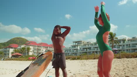 people stretching on a tropical beach before surfing