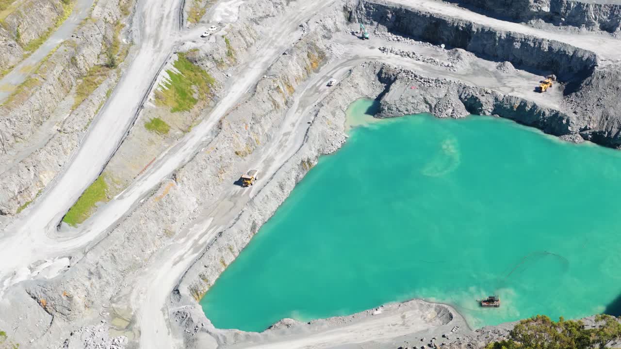 Aerial footage captures a large quarry with terraced levels and turquoise water, highlighting mining activity in Gold Coast, Australia