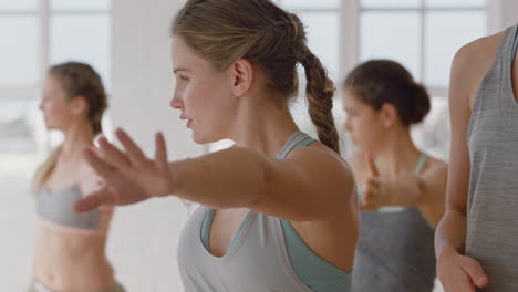 yoga class beautiful caucasian woman practicing warrior pose fitness instructor teaching group of multi ethnic women healthy meditation practice in workout studio