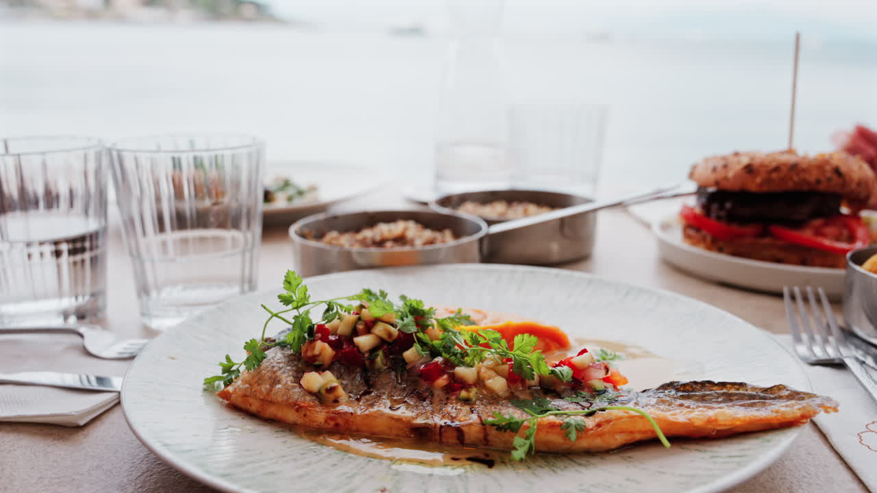 Close up of grilled fish with a sweet potato puree and a sauce on a white plate on a table at a restaurant